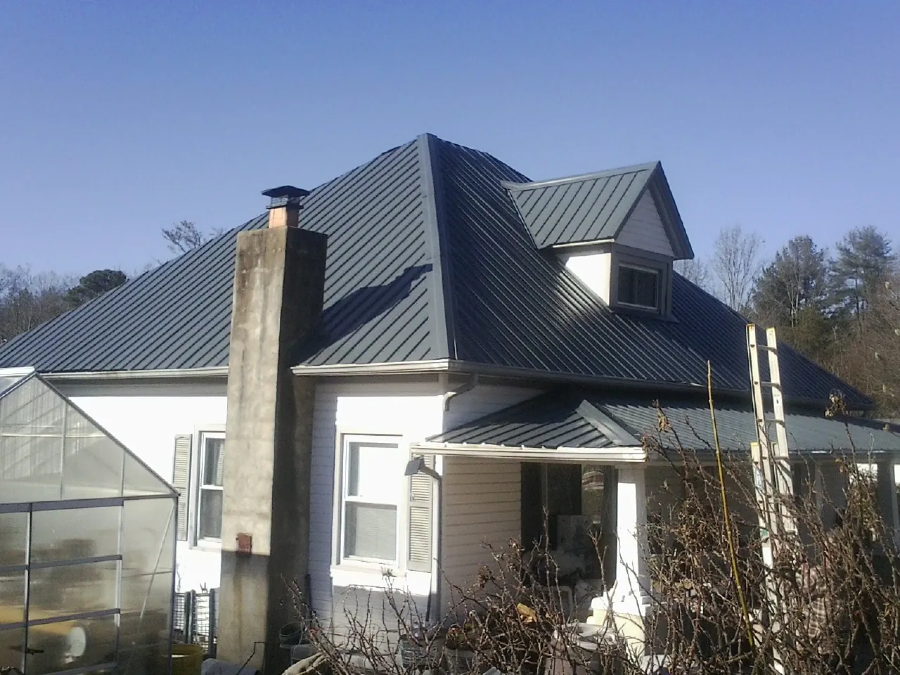 Dark blue standing seam metal roof on a white farmhouse with dormer — Slate & Tile Roof Repair by Roofing Brothers in Lockeford