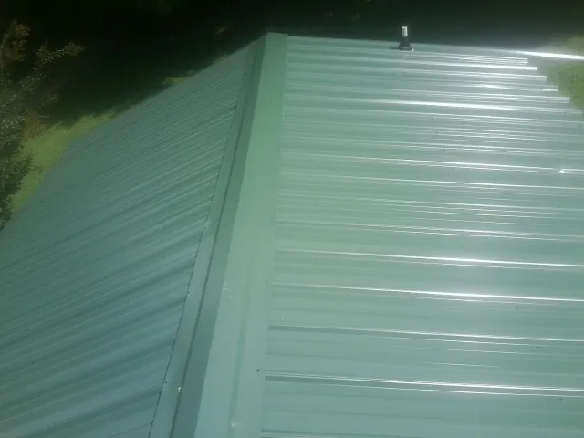 New green metal panels meeting at the ridge of a roof — Flat Roof Repair work by our crew in Lockeford