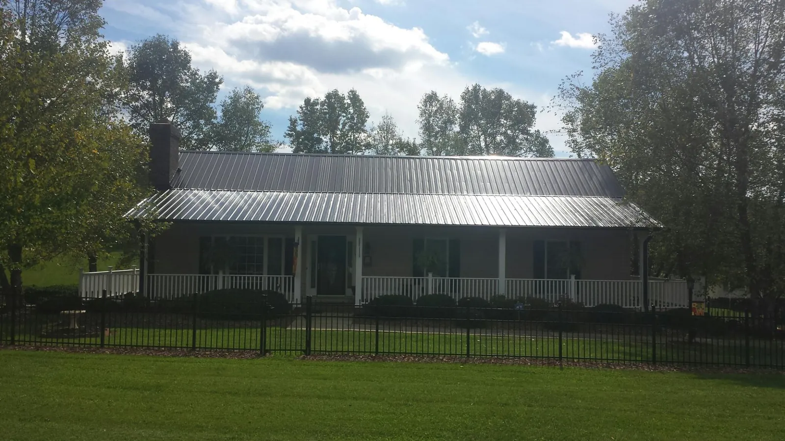 Gray metal roof on a brick ranch with a full width front porch — Gutter Guard Installation work by our crew in Lockeford