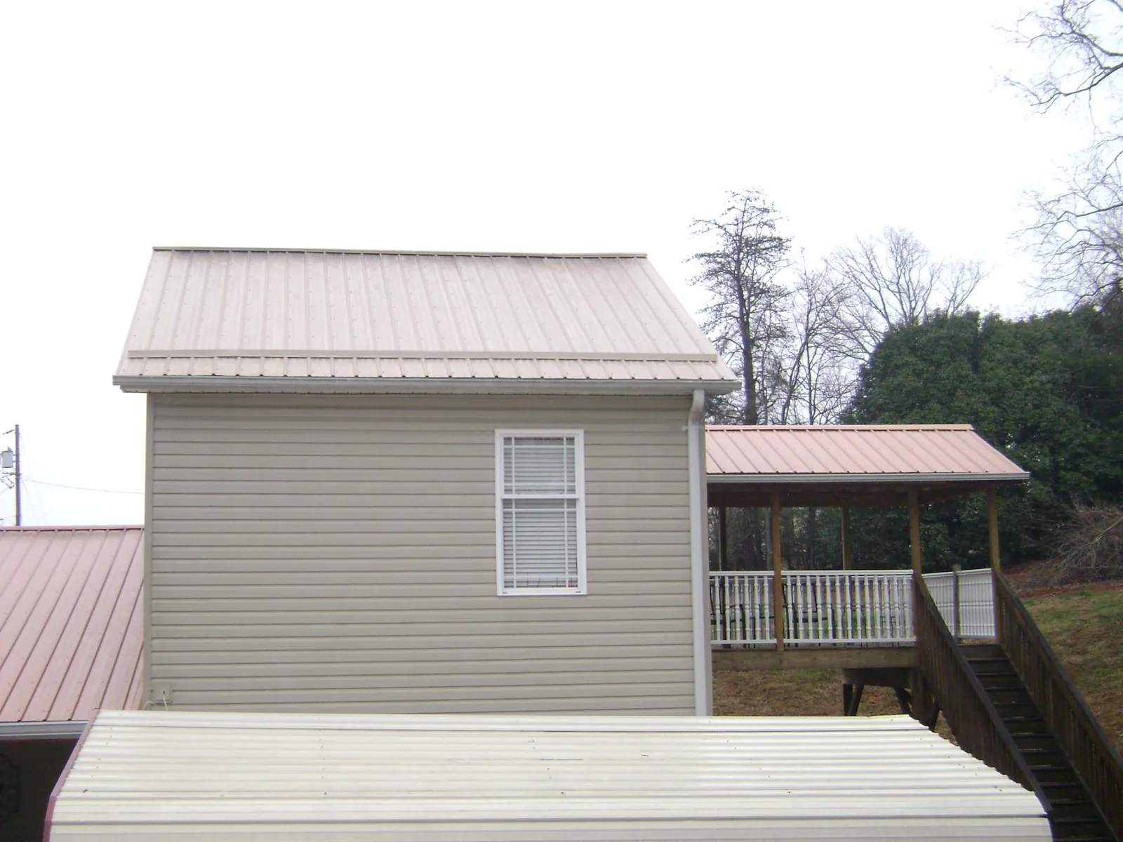 Tan metal roofs on a two story addition and attached porch, from a Roof Replacement job in Lockeford