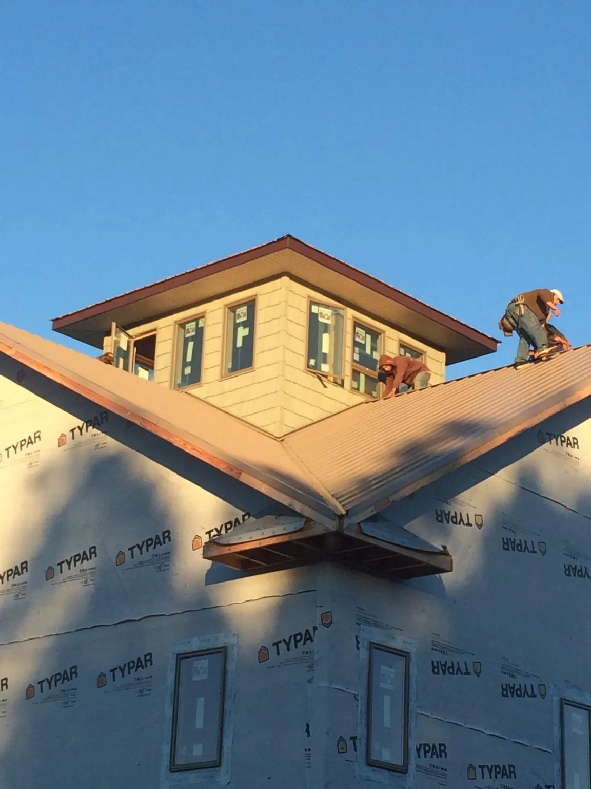 Roofers working around a rooftop cupola on a new metal roof at sunset — Roof Waterproofing in Lockeford by Roofing Brothers